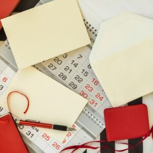 Calendar planner page, envelope, letter, greeting cards, notebook and pen. Top view