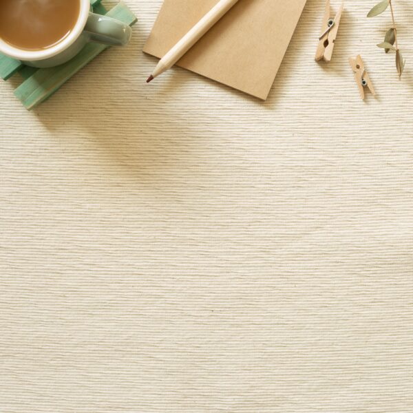 Work and study place. Cup of coffee, notepad, pencil, clip on beige fabric background. flat lay, top view, copy space