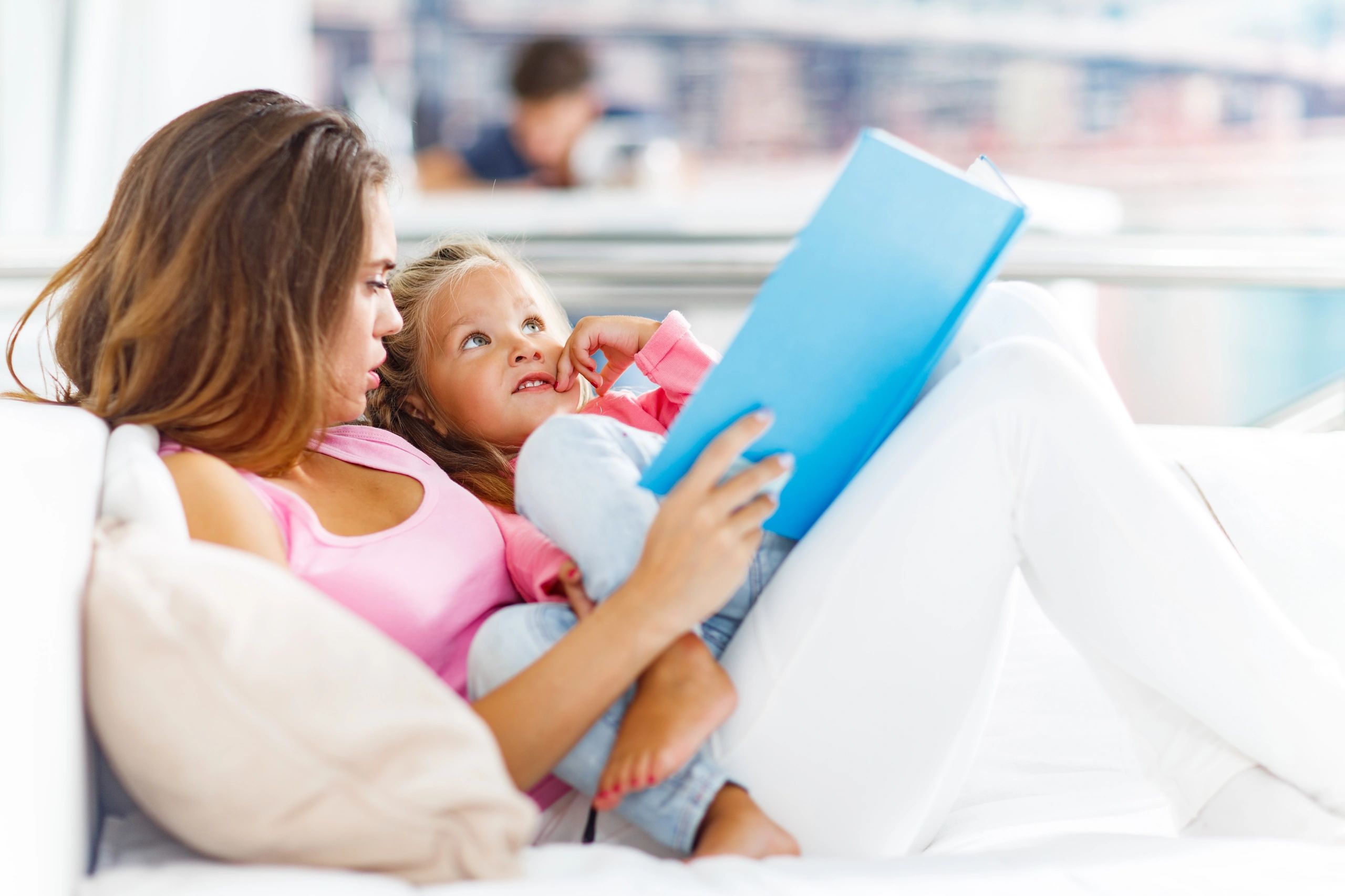 Mother reading a book with her daughter at home