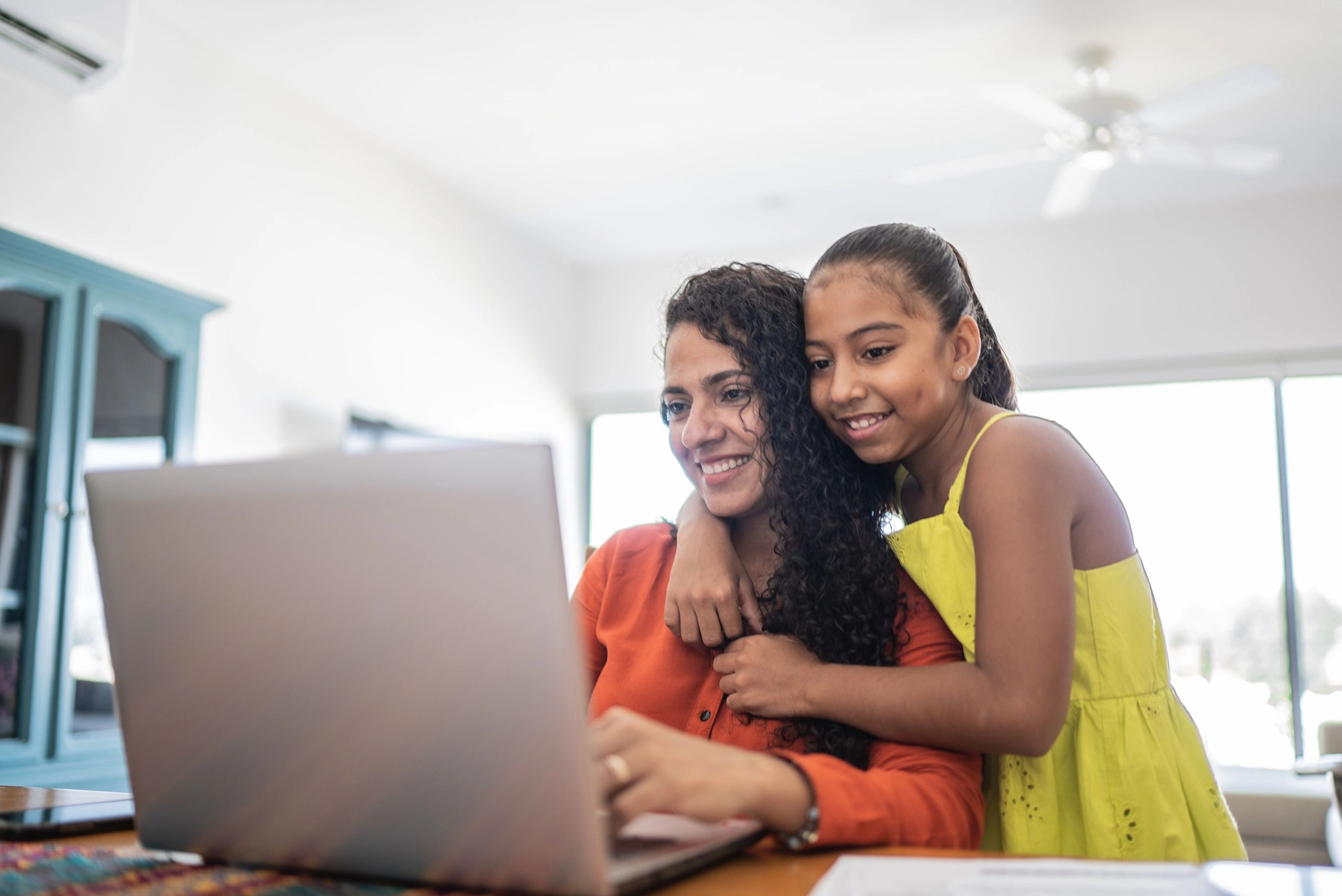 Mother and daughter using a laptop together at home
