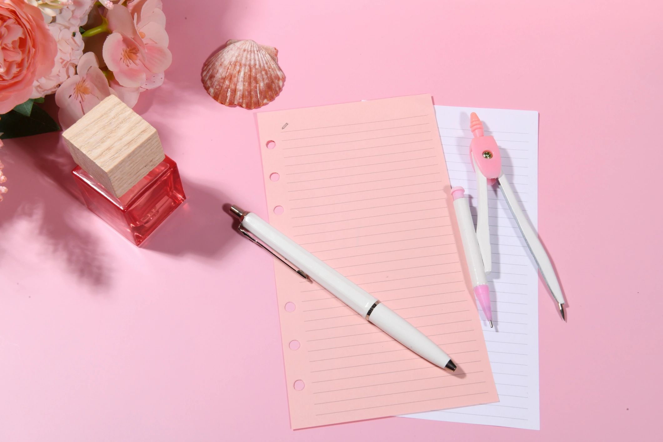 Notes and perfume on a pink surface